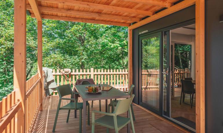 Holzterrasse mit Tisch, Stühlen und Waldblick.