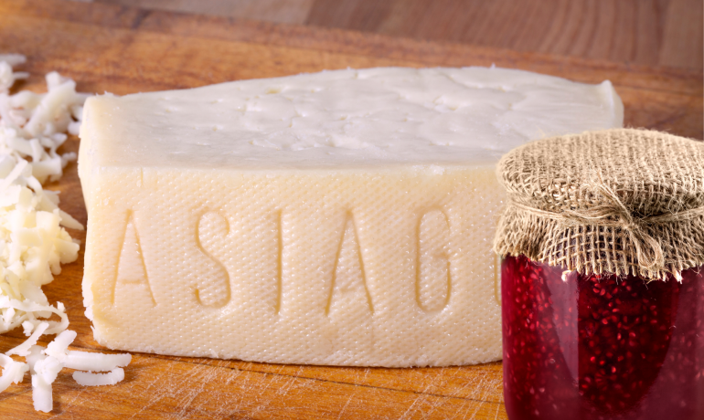 Formaggio Asiago con marmellata su tagliere di legno.