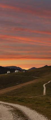 Sentiero di montagna al tramonto con cielo rosso, paesaggio mozzafiato.