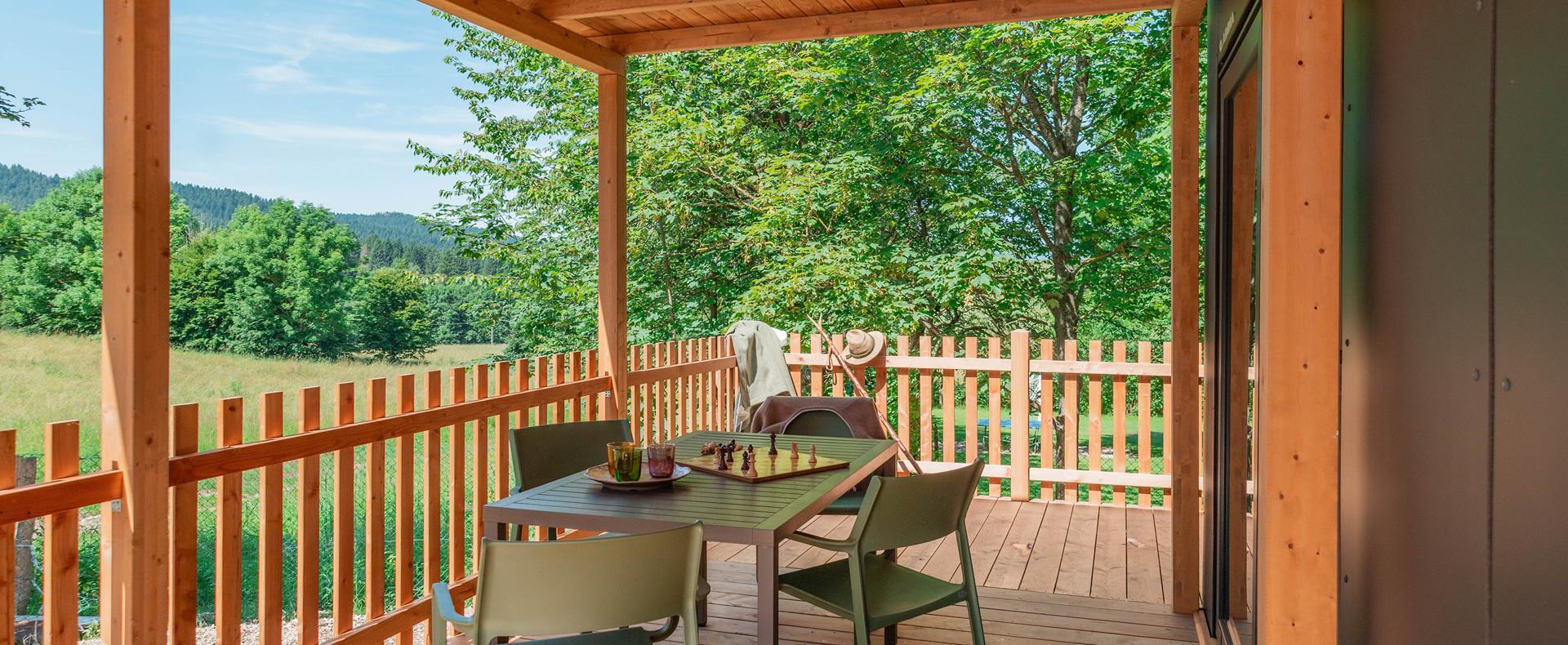 Terrazza in legno con vista su alberi e colline.