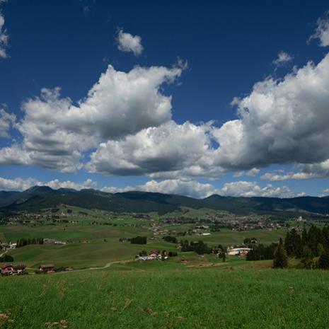 Paesaggio collinare con cielo nuvoloso e villaggi sparsi.