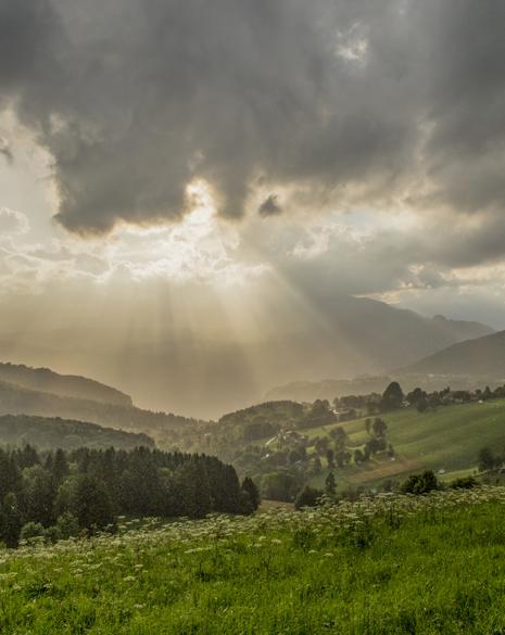 Paesaggio montano con raggi di sole che filtrano tra le nuvole.